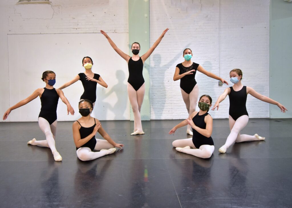 10-12 year old dancers pose symmetrically in ballet clothes