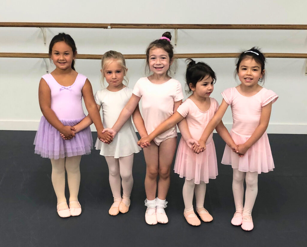 5 dancers age 3-6 stand holding hands with their arms crossed as in "Swan Lake."
