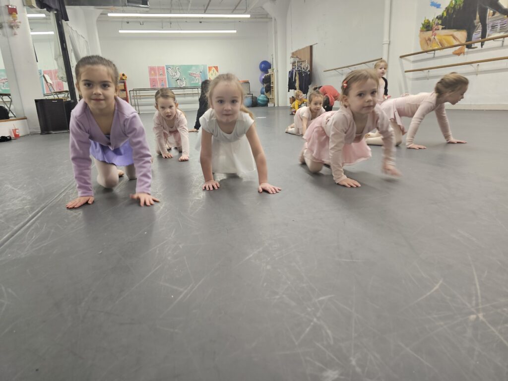 Dancers age 3-5 crawling toward the camera and smiling